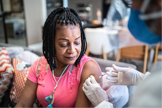Doctor administering vaccine to mature woman