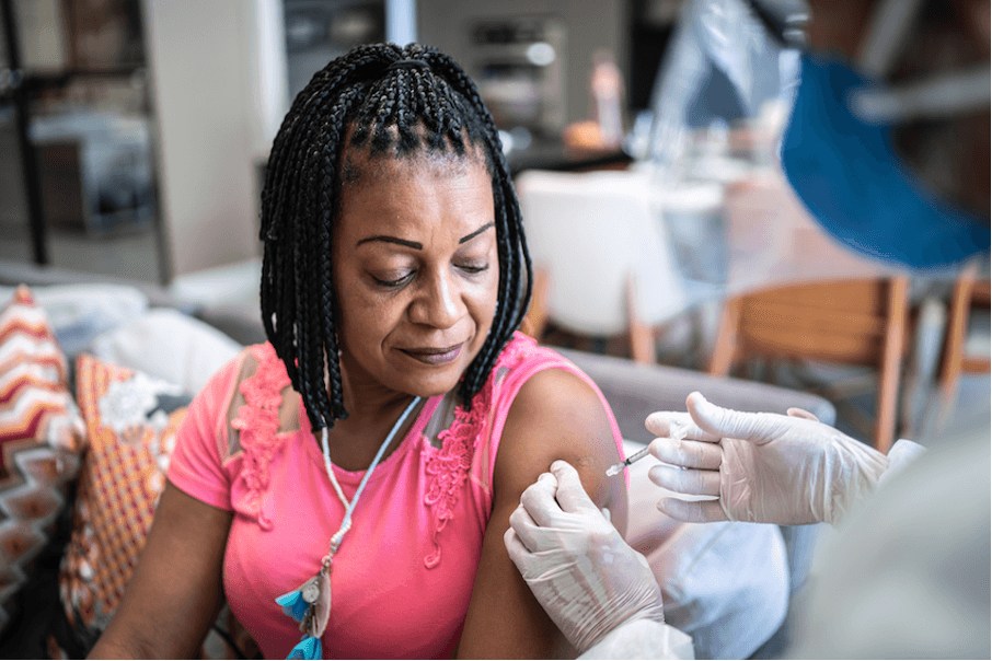 Doctor administering vaccine to mature woman