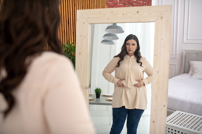 Woman looking at body in the mirror