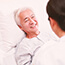 older Asian man in hospital bed being seen by doctor 