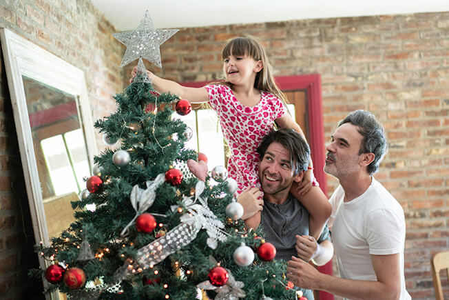 gay male couple with daughter decorating tree