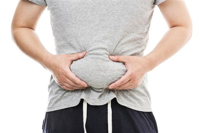 Man grasping excess weight in belly area Man grasping excess weight in belly area