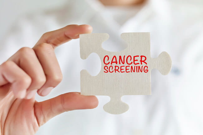 person holding cancer screening puzzle piece