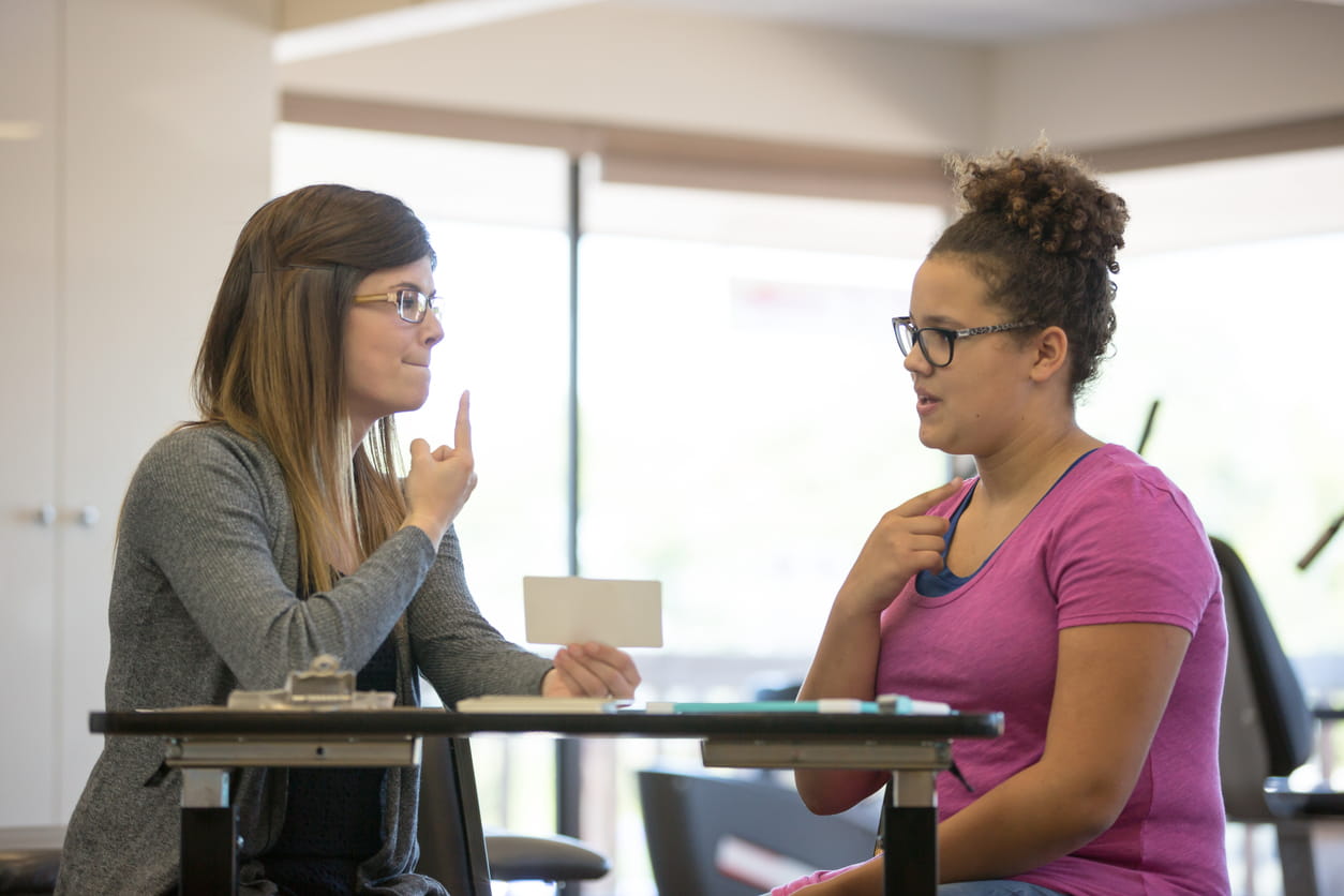 Speech therapist teaching woman with vocal exercise