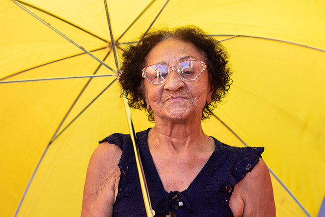 Elderly woman using umbrella for shade