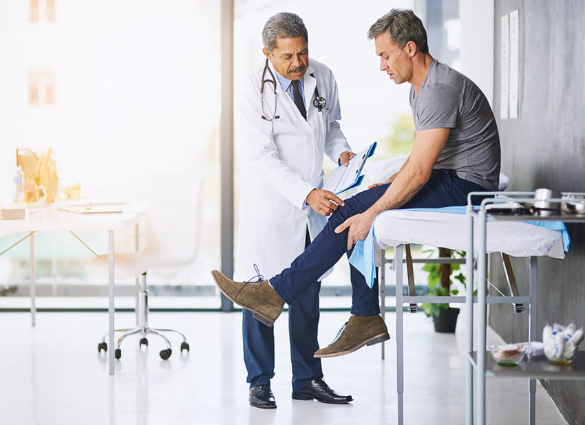 doctor examining his patient who is concerned about his knee