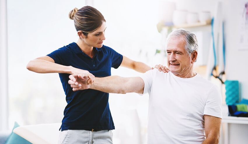 female physical therapist working with a senior male patient