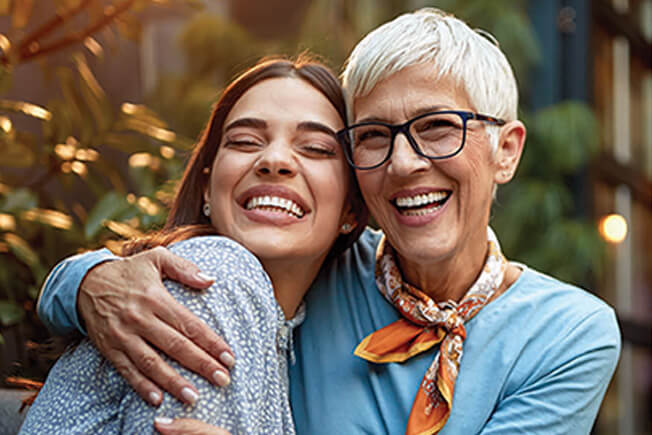 portrait of a senior mother and adult daughter, hugging, smiling