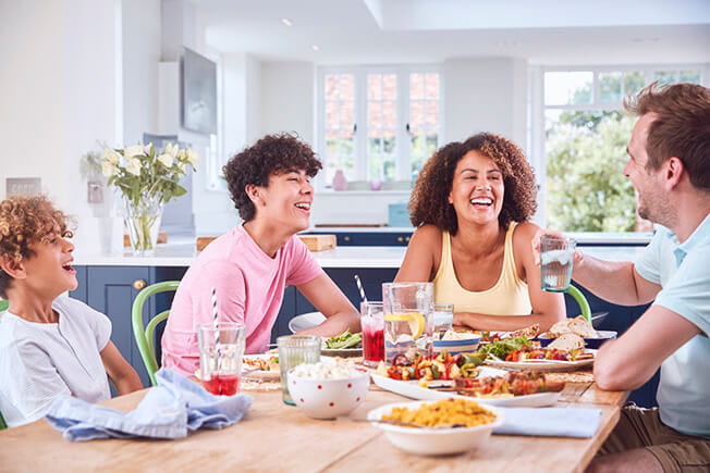 Family sitting around table at home eating meal together