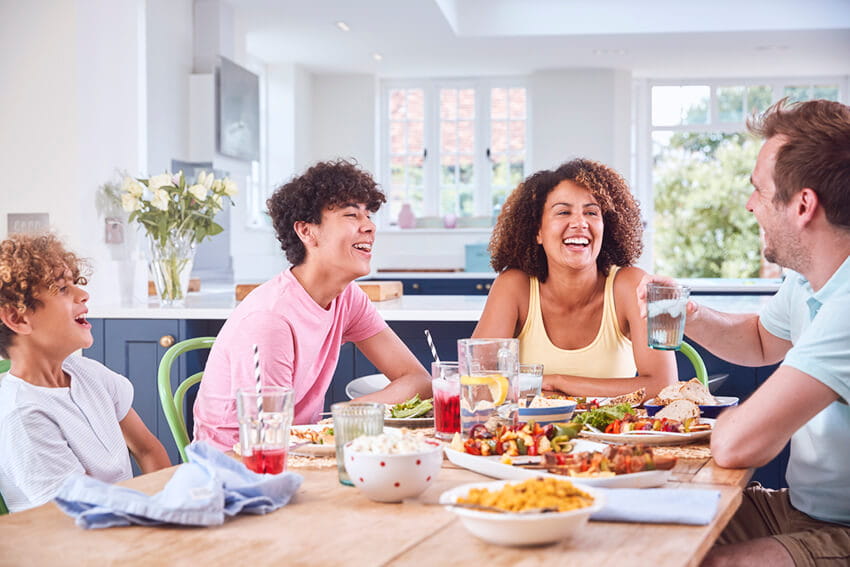 Family sitting around table at home eating meal together 