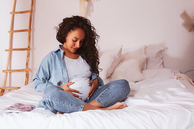 Pregnant woman sitting on bed