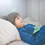 Kid in pajamas lays in bed feeling sick with stomach bug
