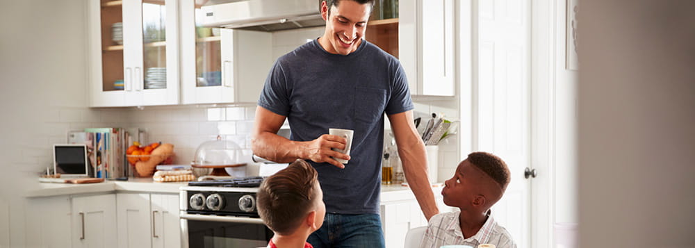 Two children in a kitchen with an adult.
