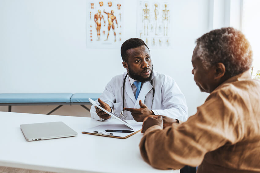 Male doctor speaking with an older male patient.