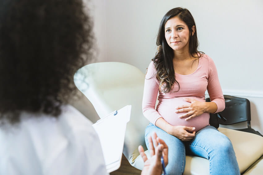 Pregnant woman speaking with a doctor.