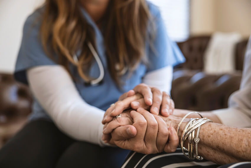 Nurse holding an older woman's hands