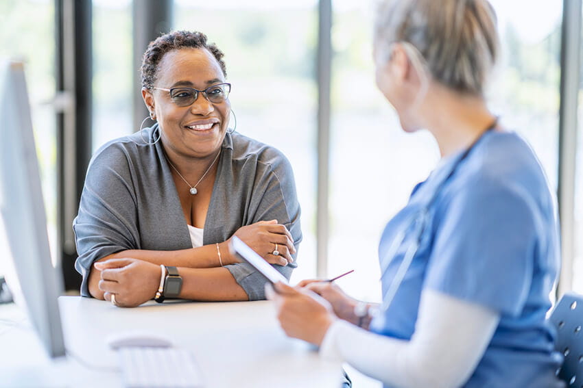 Older woman speaking with younger female nurse.