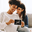 Same-sex pregnant couple holding up their ultrasound scan.