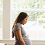 Pregnant woman standing at a window.