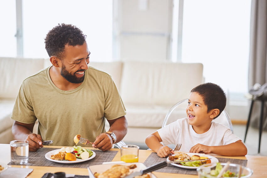 Father and son eating a healthy meal at home.