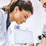 Hospital phlebotomist collecting blood sample from patient in lab. 