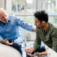 Older man with his hand on the arm of a younger man in therapy.