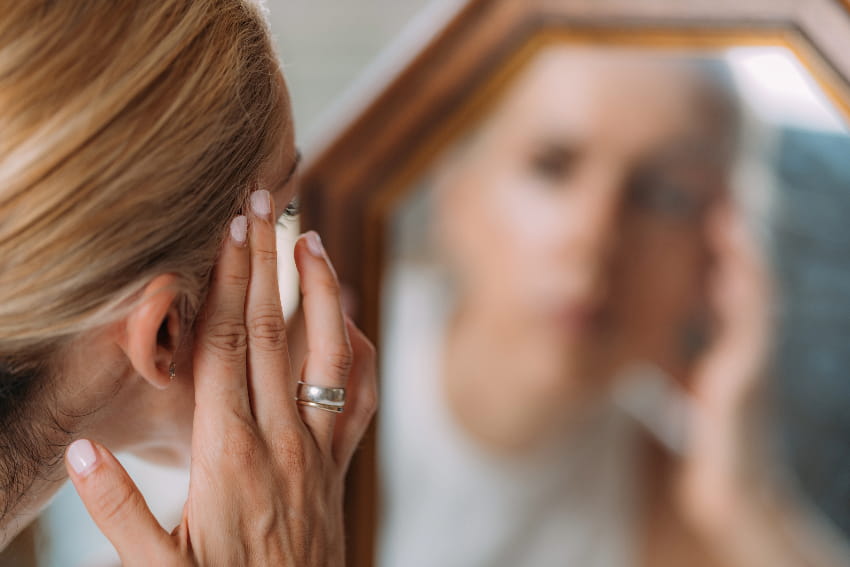 Woman looking in a mirror with her hand no her face.