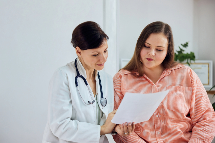 A female doctor looks at paperwork with a woman.