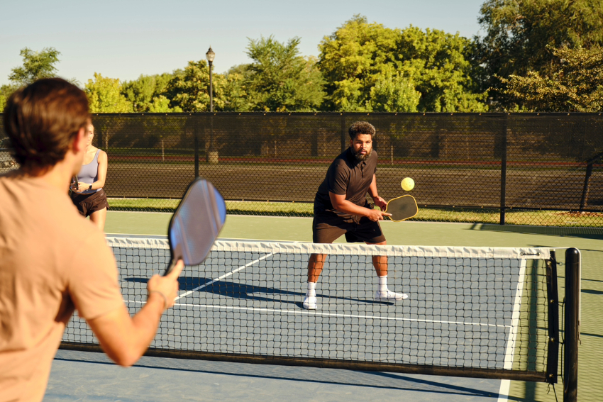 Young adults playing pickleball on a public court