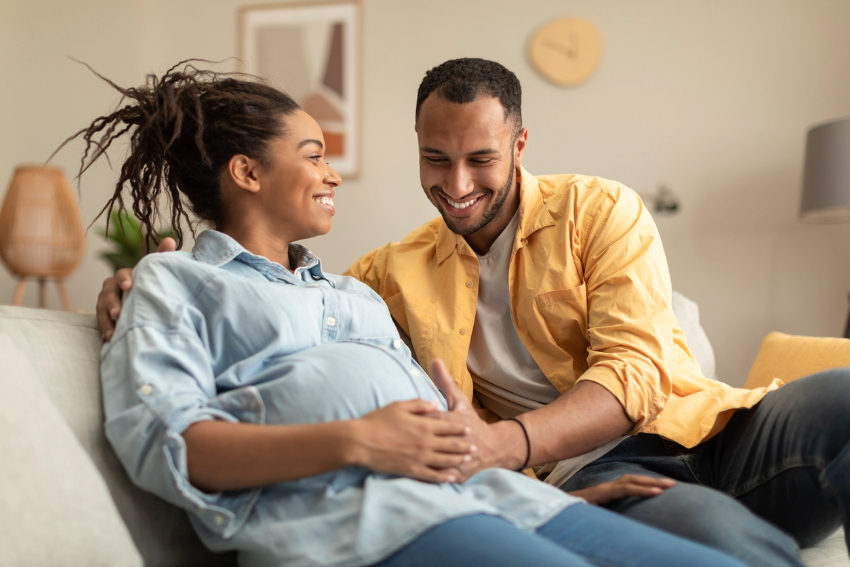 Happy pregnant woman sitting on a couch with a happy man.