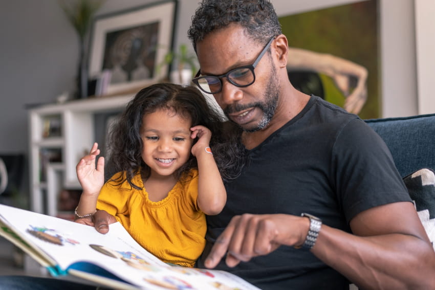 Father reading book with daughter.