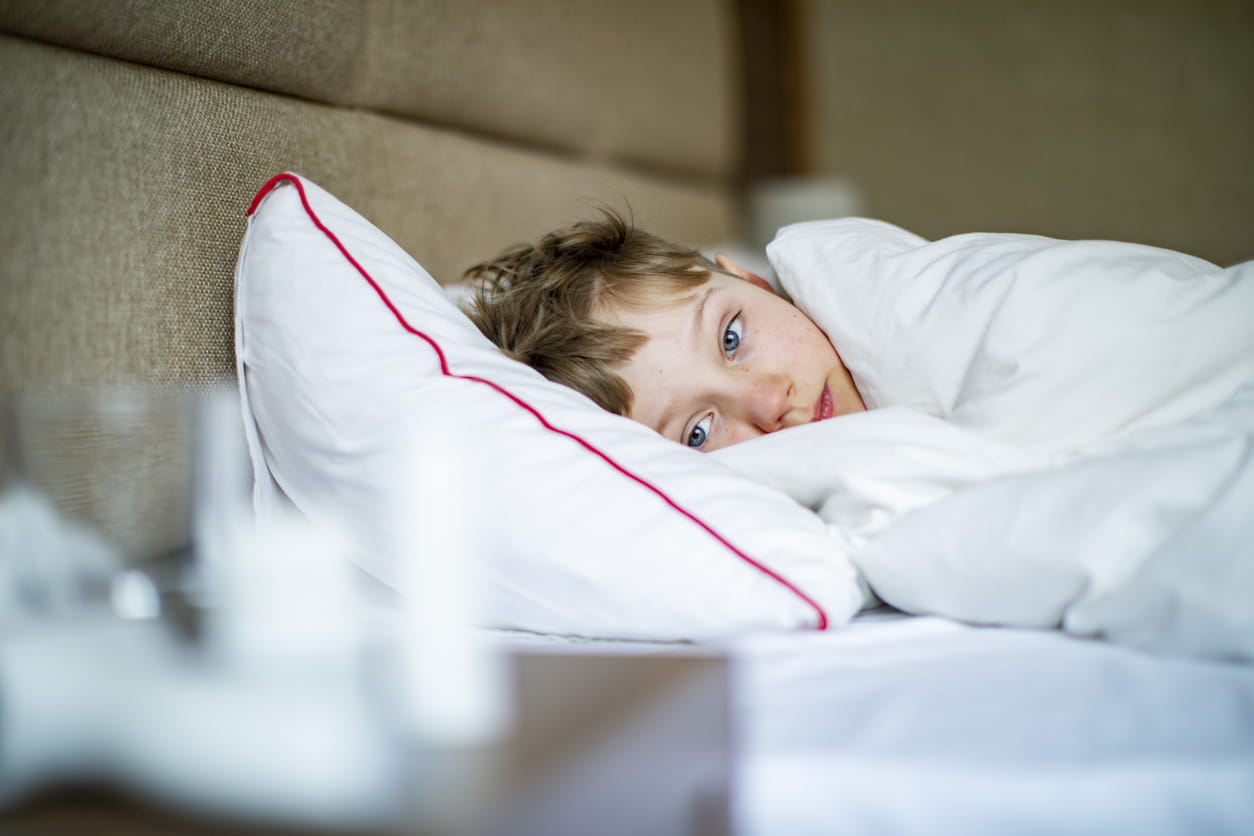 Little boy laying in bed with a flu.
