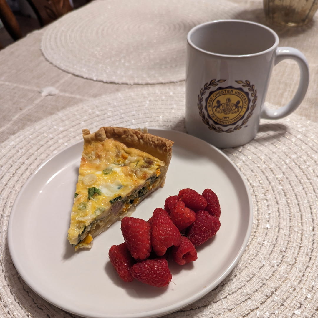 slice of sausage veggie breakfast quiche, raspberries and coffee