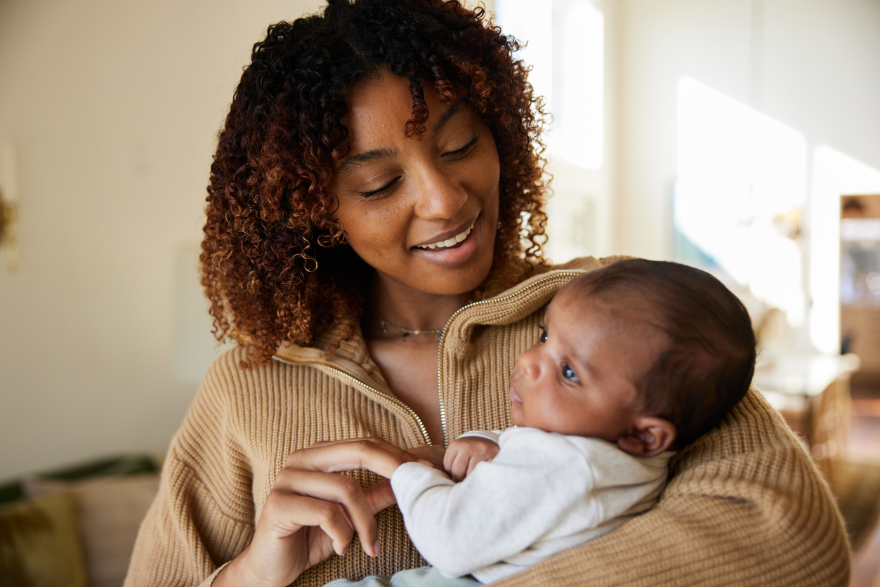 Smiling mom standing at home with her baby son in her arms