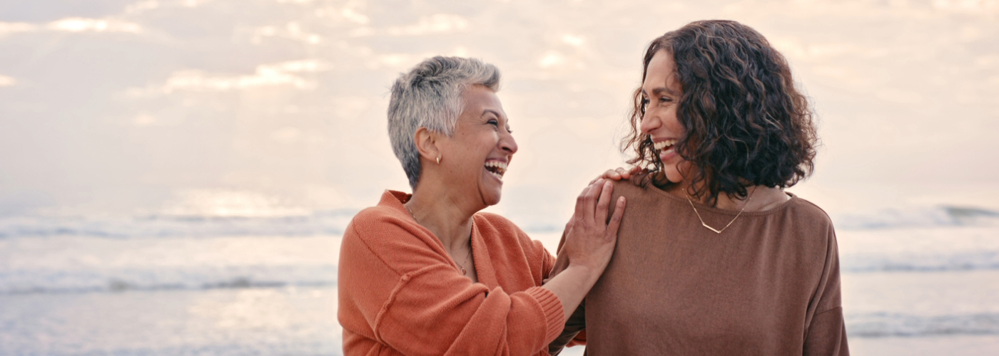 Two women at the beach smiling together.