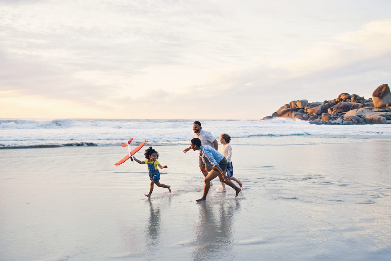 Man running on beach with his three children. 