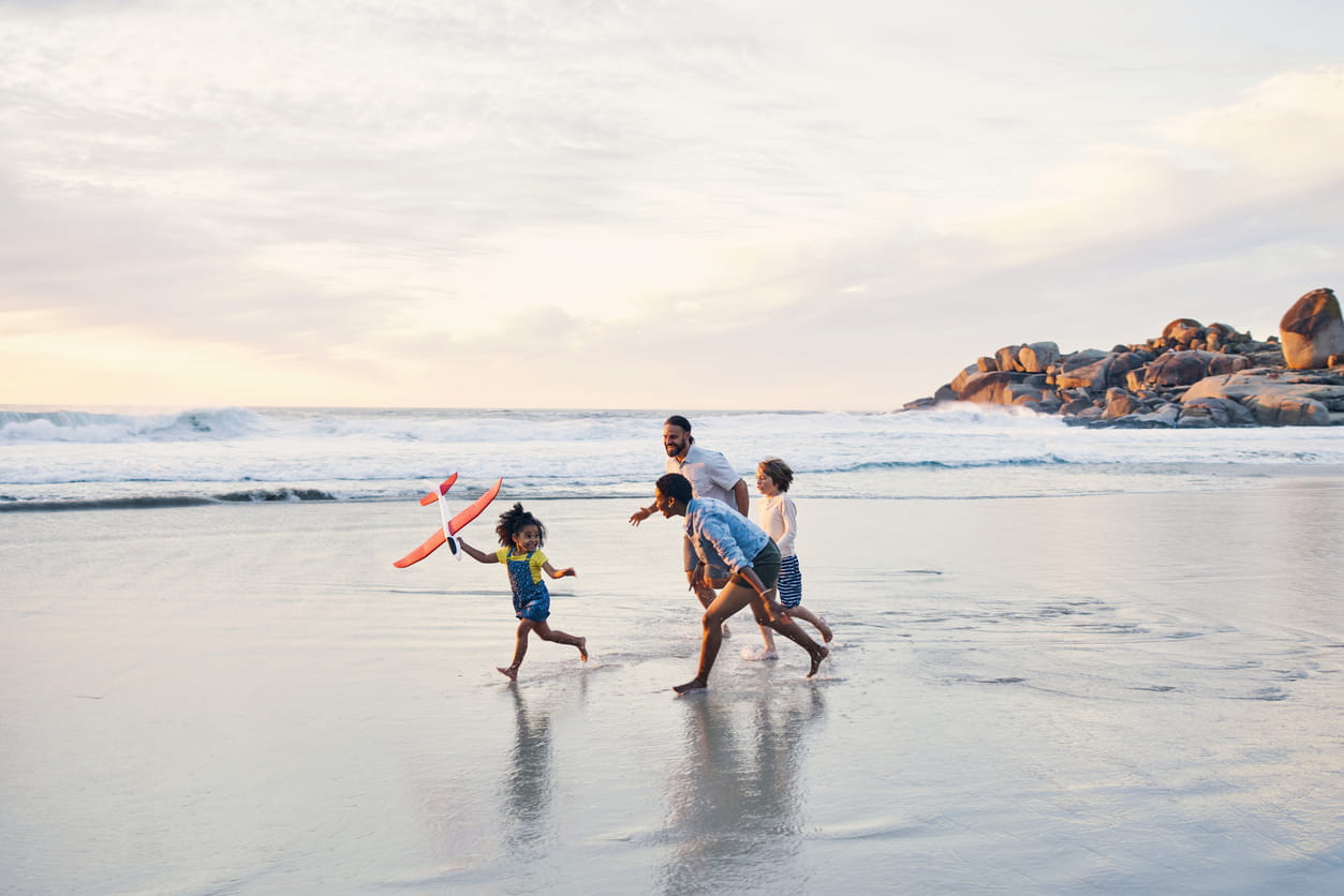 Man running on beach with his three children.