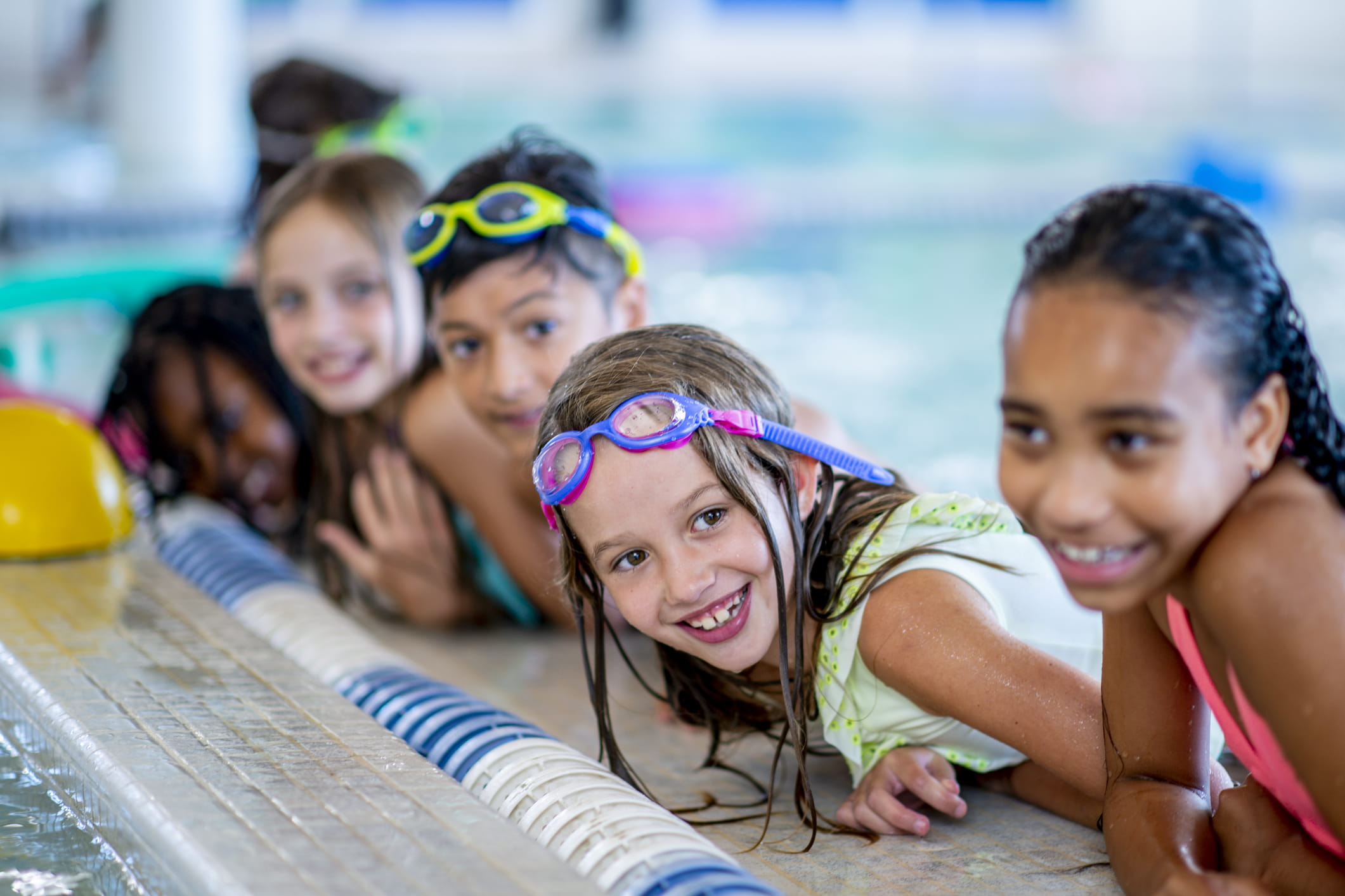 Children lined up at the edge of an indoor pool.