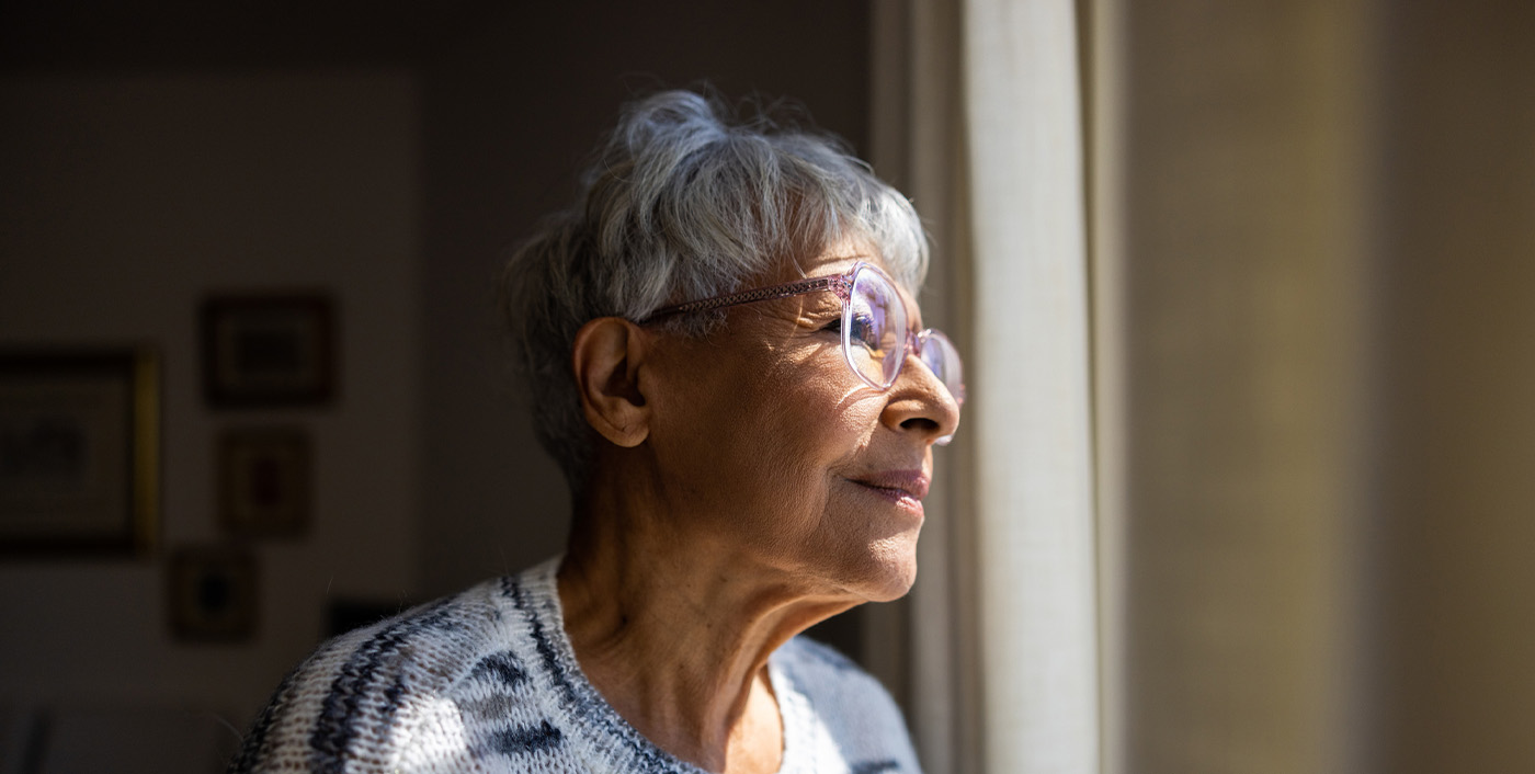 Senior woman looking out the windows of her home