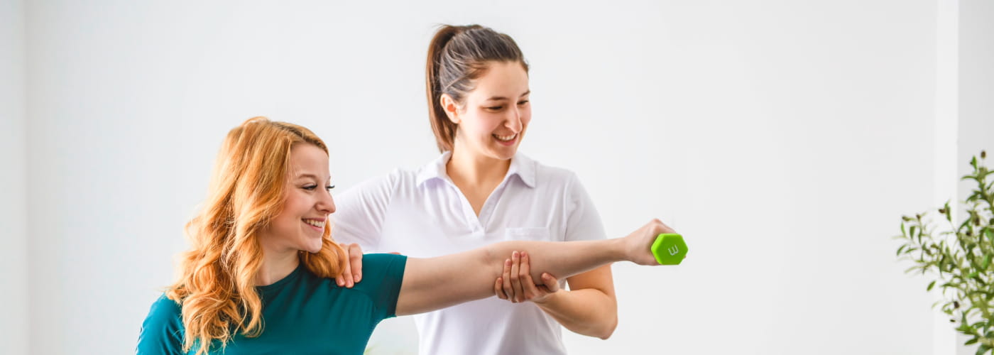 Physical therapist working with a client who is holding a dumbell