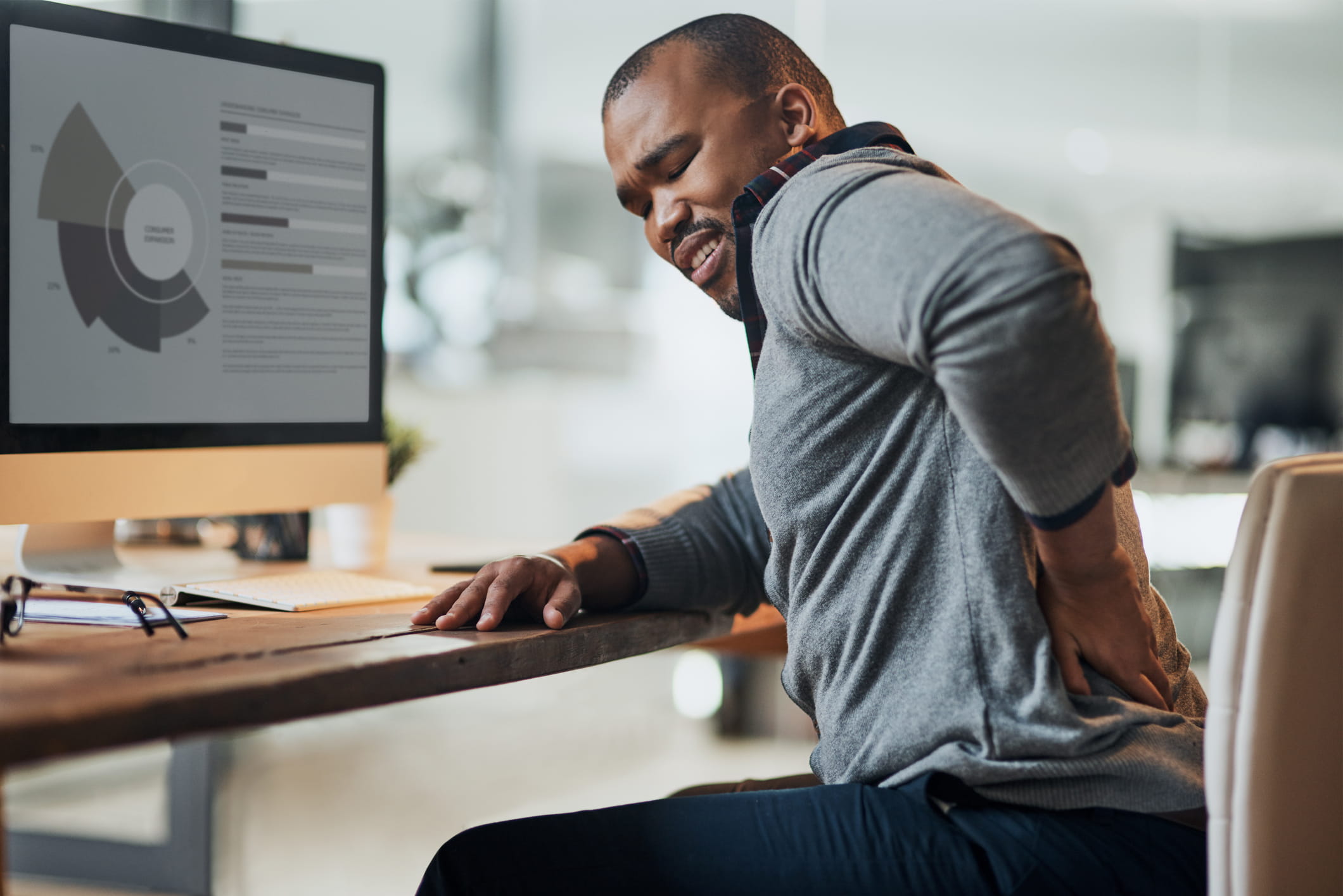 Man sitting at a desk experiencing back pain