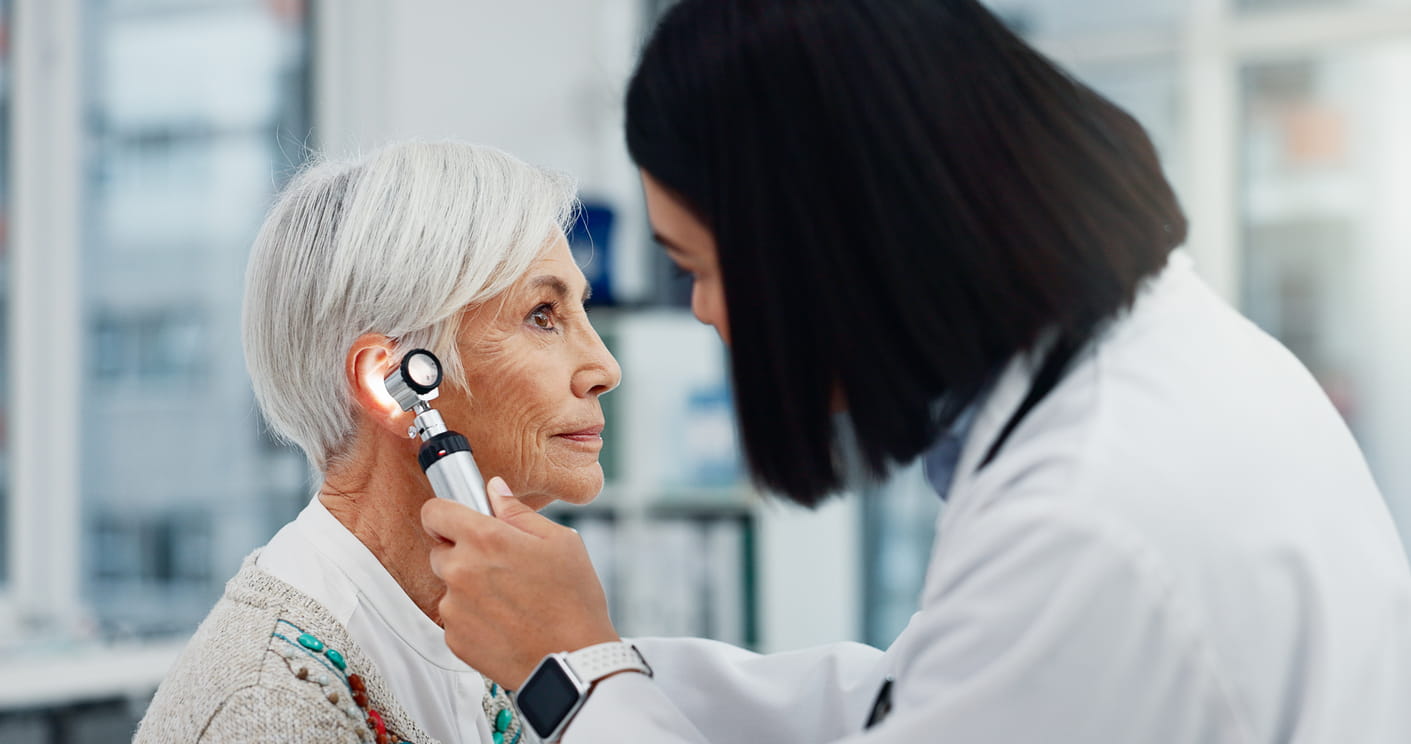 Senior woman, doctor and otoscope for ear, hearing test and exam