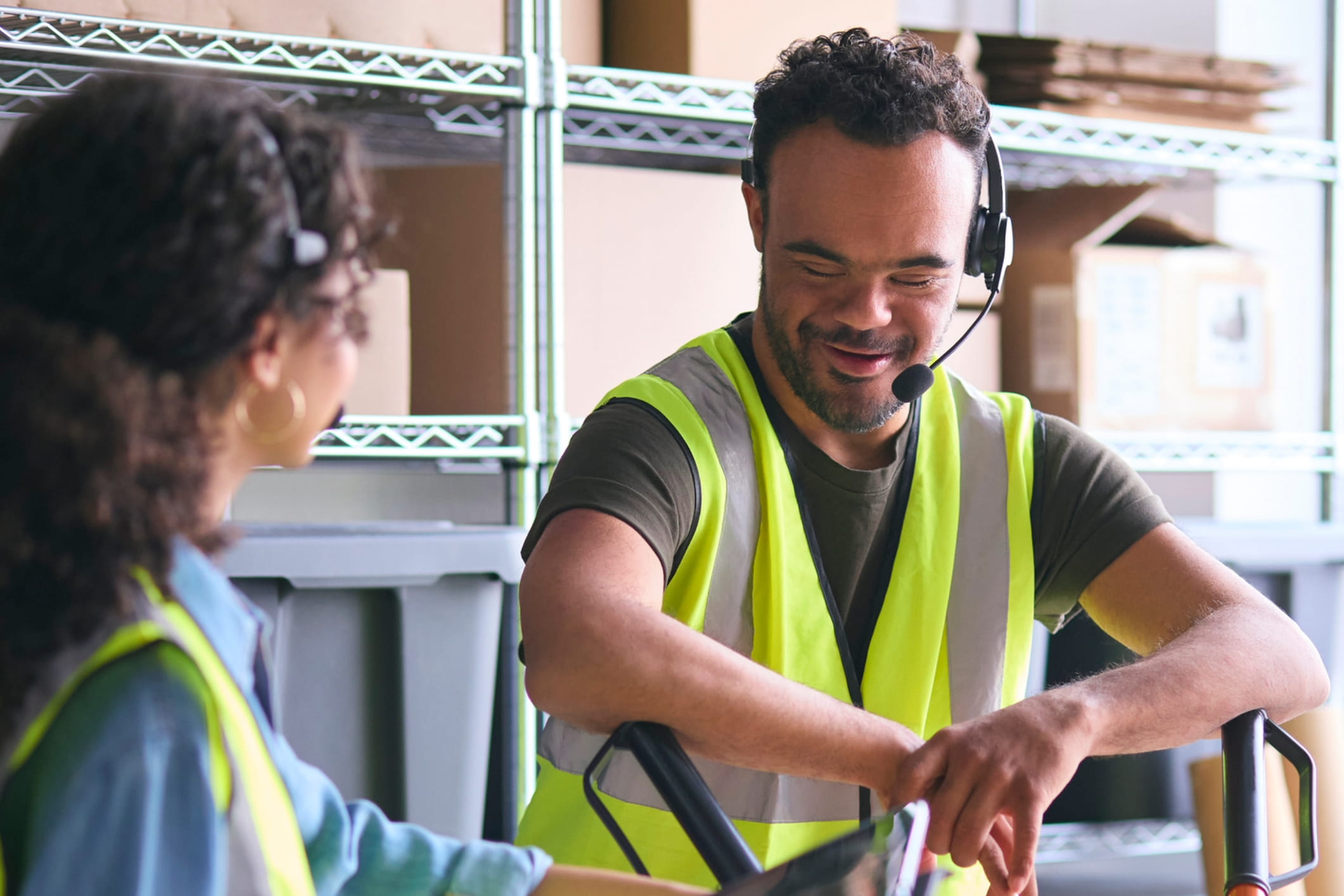 Woman Using Digital Tablet And Male Colleague In Warehouse Wearing Headsets