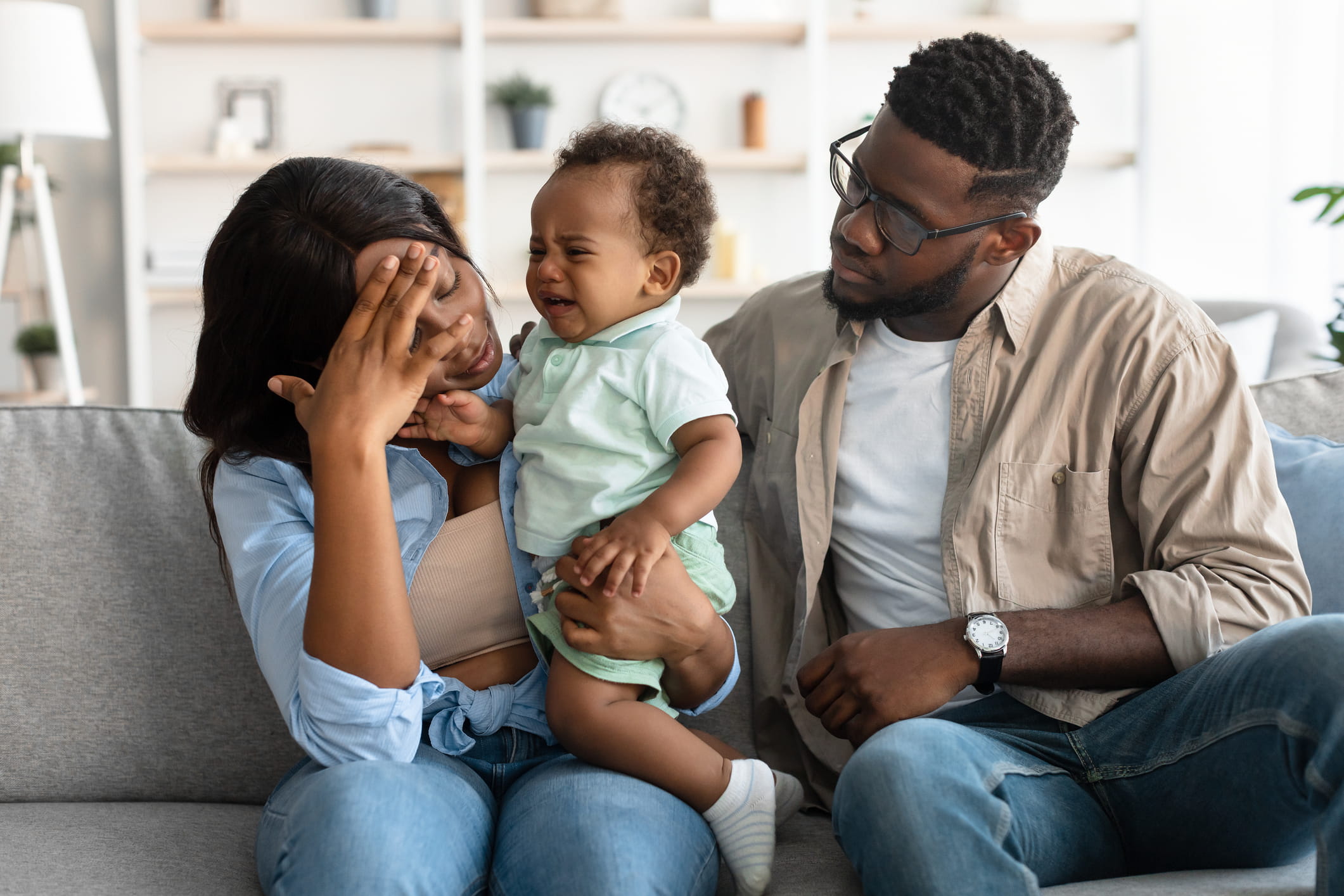 parents sitting with crying kid on sofa
