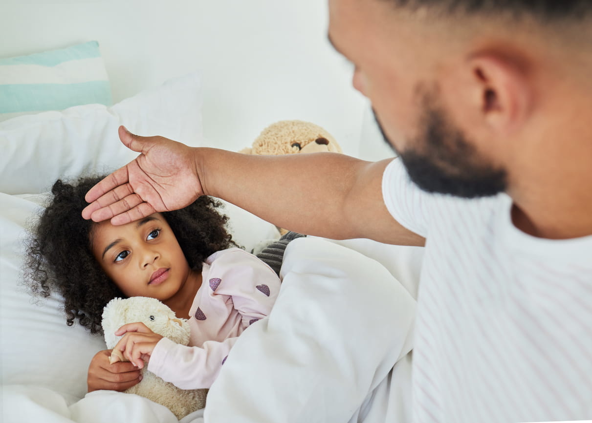 Dad caring for sick daughter in bed