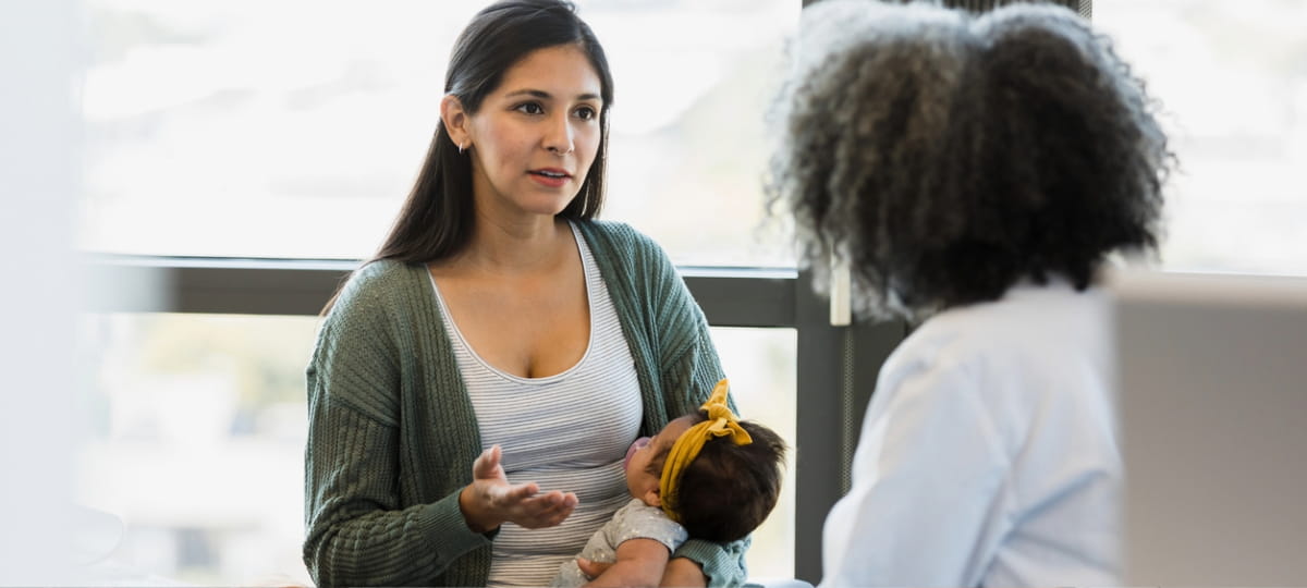 Woman with newborn talking to physician