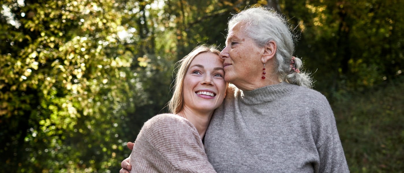 Grandmother and adult granddaughter embracing in garden