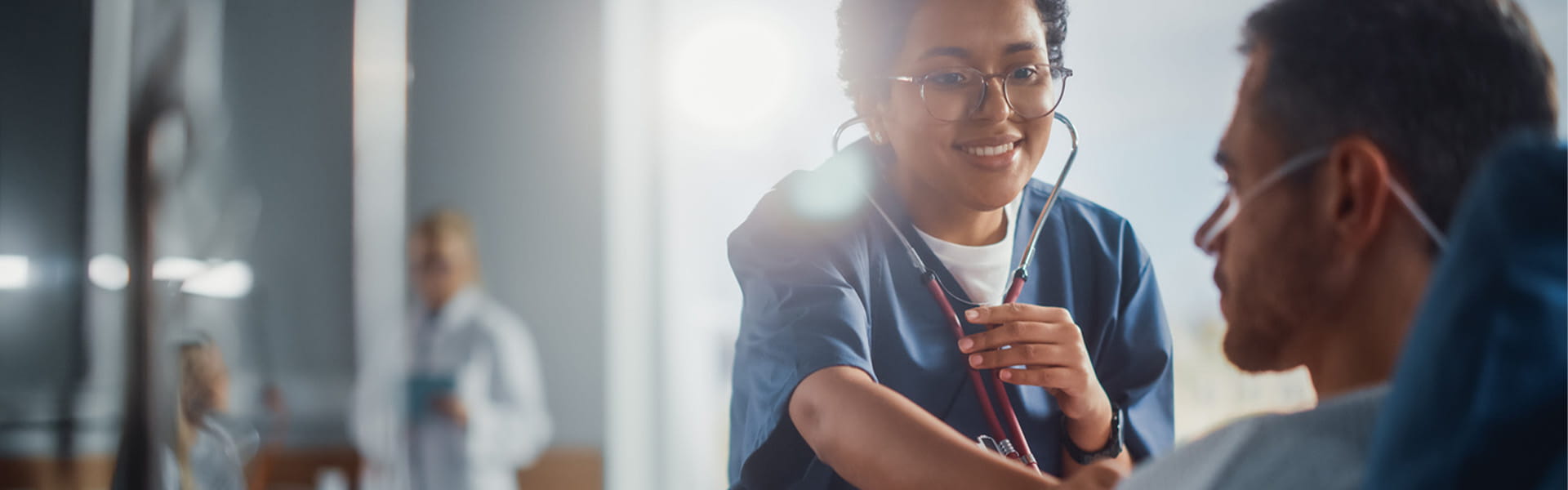 Friendly nurse using stethoscope with hospital patient