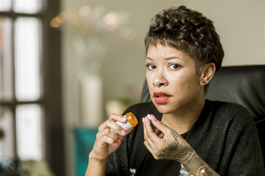 Worried woman with an opioid prescription pill and bottle in hand