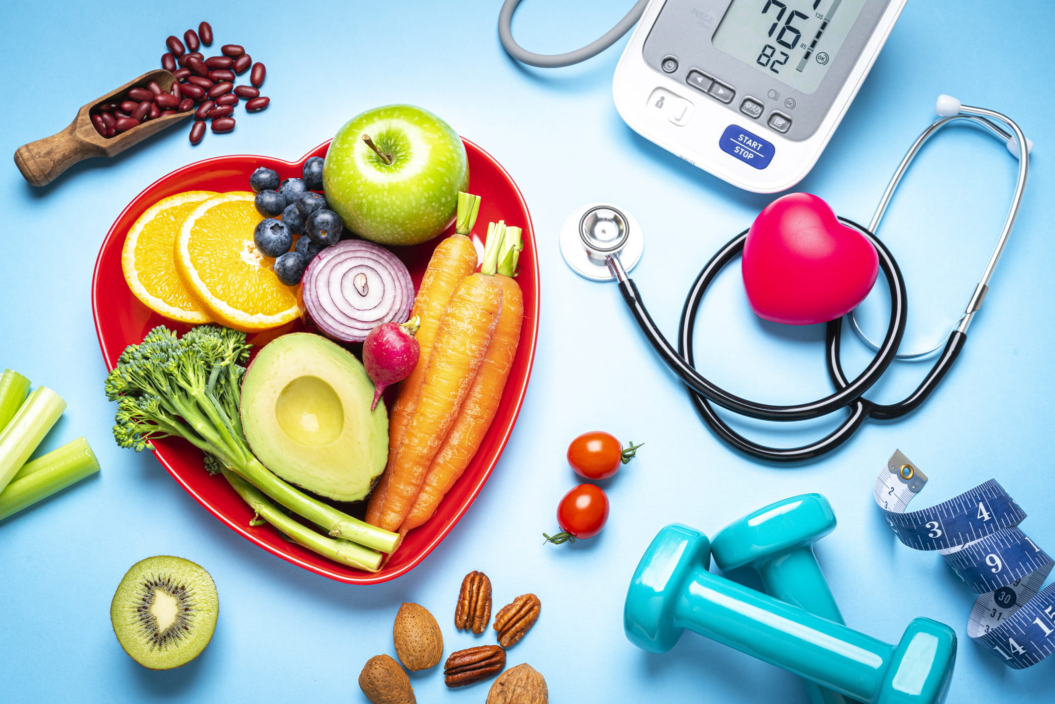 Items representing a healthy lifestyle: Fruits and vegetables, hand weights, stethoscope and blood pressure machine